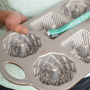 The Ultimate Bundt® Cleaning Tool,  cakelet pan being cleaned with the bristle end of tool