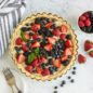 Overhead baked fruit tart in Quiche and Tart Pan with berries in background