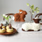 Easter scene of Baked Bunny Cake on cake stand, decorated Lamb Cake plated, Shortcake Baskets with chocolate bunnies