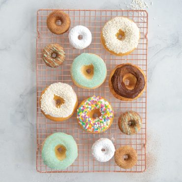 Assorted classic and mini baked donuts on cooling grid