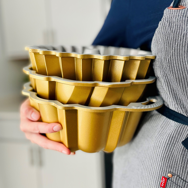 Person holding 3 stacked gold Bundt Pans