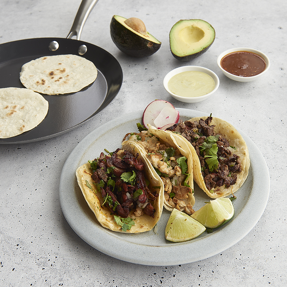 3 Tacos on plate with Crepe Pan with cooked tortillas in background