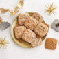 Glazed Gingerbread Cookies on gold plate surrounded by gold starburst ornaments, golden ribbon, and cookie stamps.