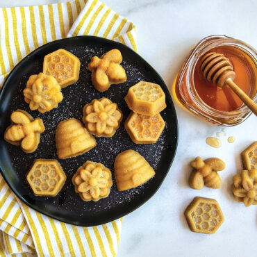 Baked bee bites on black plate, with jar of honey