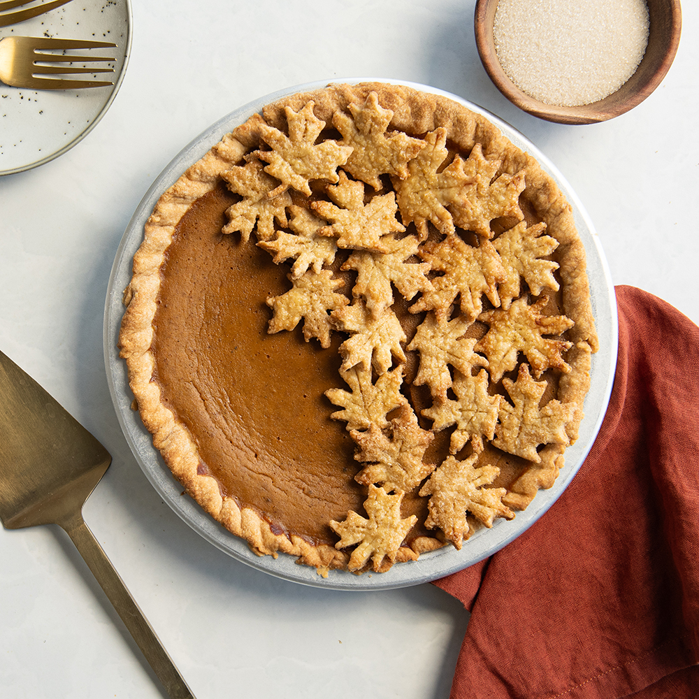 Overhead image of baked maple pumpkin pie with sugared leaves topping design