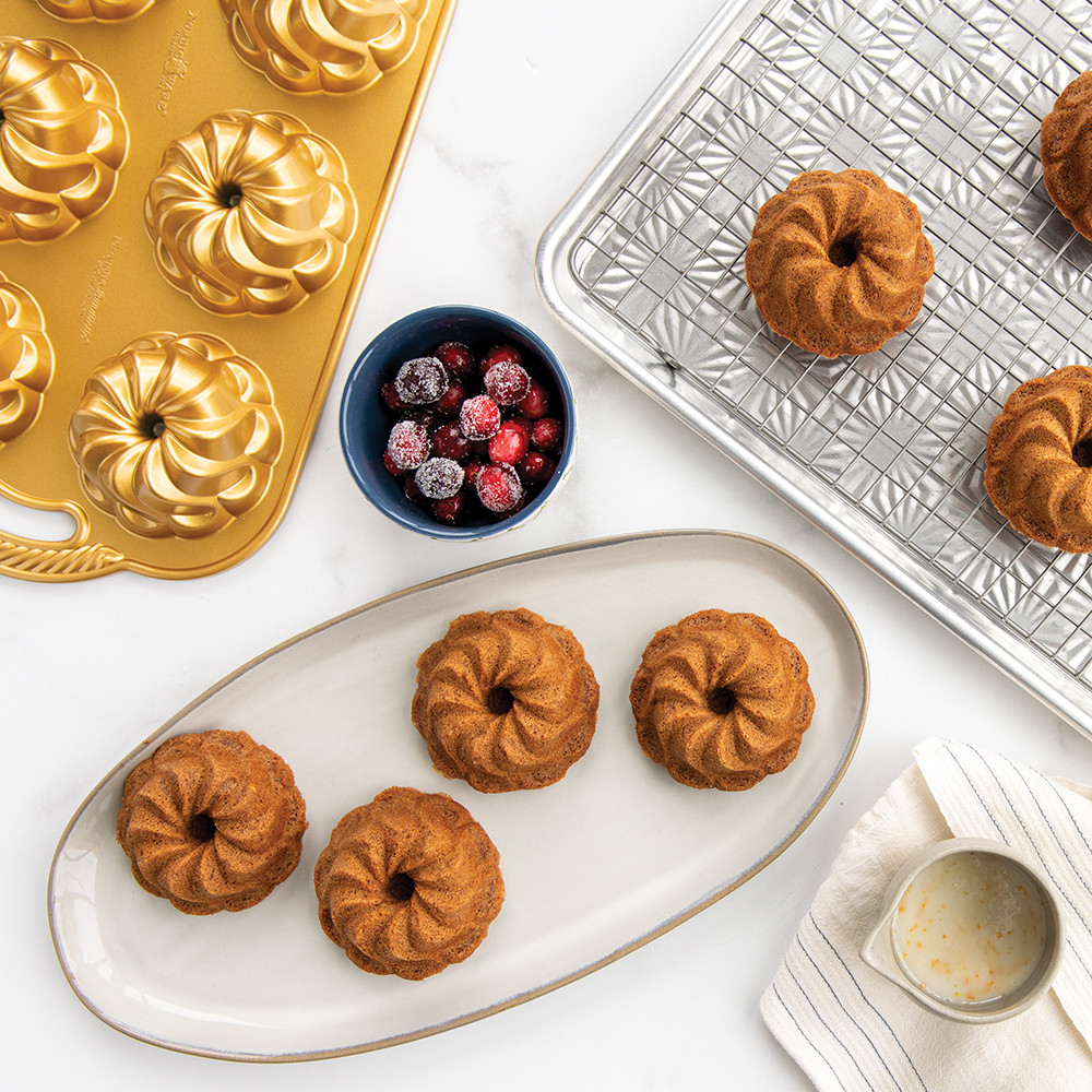 Image of baked Piourette Bundtletts, some plain on a platter and some one a cooling rack.