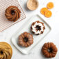 Classic Bundt Duet Cakes, plated, with bowl of cinnamon and cooling rack, orange slices. and pan