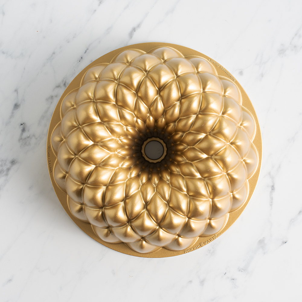 Image of Kaleidoscope Bundt Pan in gold exterior, overhead on marble surface