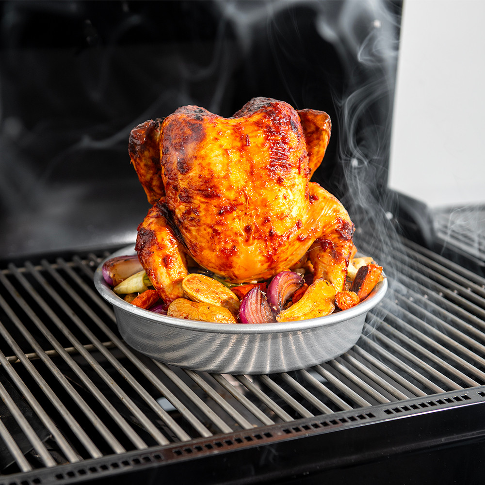 Image of grilled chicken on chicken roaster filled with veggies
