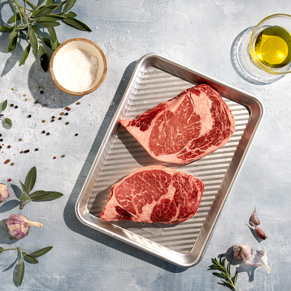 Image of raw steak on 3-in-1 aluminum tray with ingredients around it.