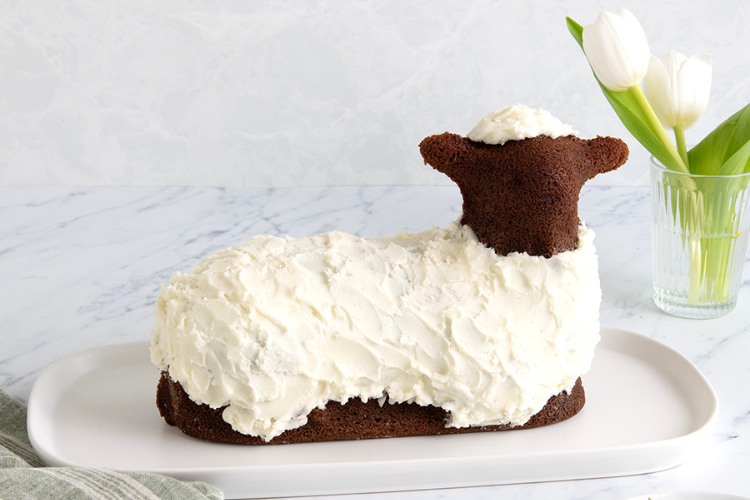 Baked chocolate lamb cake with white frosting decoration on platter